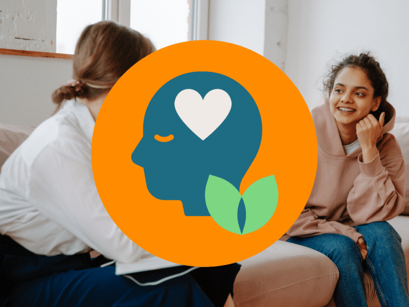 A photo of two women sat on a sofa. One woman is a coach and the other is a client.