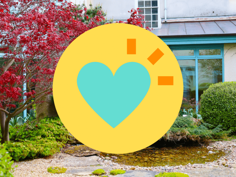 A photo of the Penny Brohn UK garden with the Lift Your Spirits pillar icon over the top