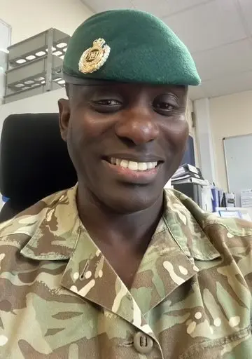 John smiling to camera in military uniform and beret.