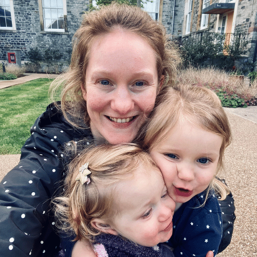 Milly outdoors holding her two young children.