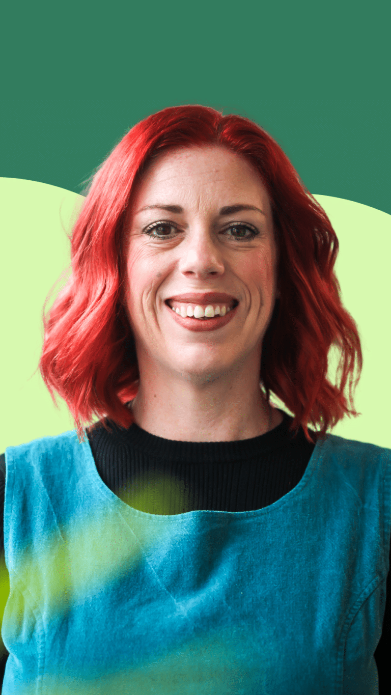A photo of our Trustee Emma. She has red hair, a blue dress and is smiling for the photo